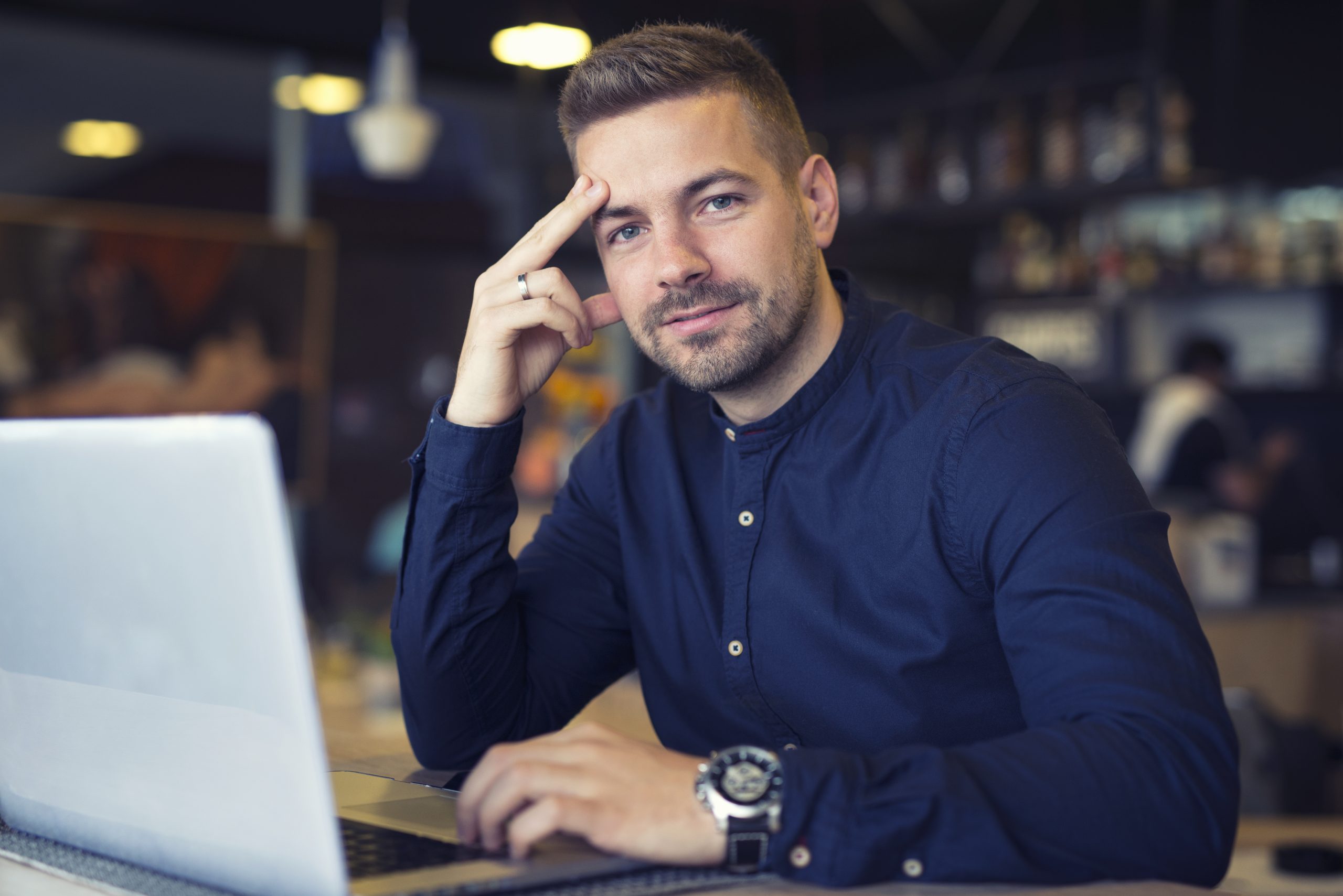 Young caucasian businessman siting at cafeteria with laptop computer on the table.